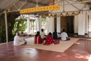 शिव मंदिर में व्यक्तिगत ध्यान करते भक्तजन।