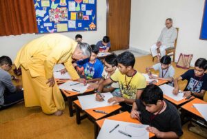 Brahmachari Vinayananda assists a boy in his 3D drawing.